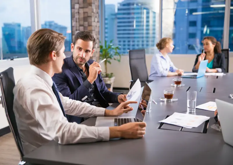 Colleagues share plans around a long table while adding their company details to the local directory online